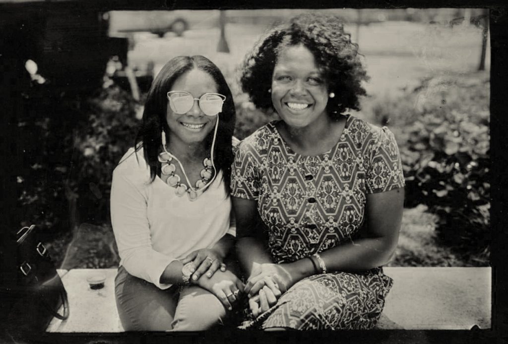 A picture of two women sitting down and smiling at the camera